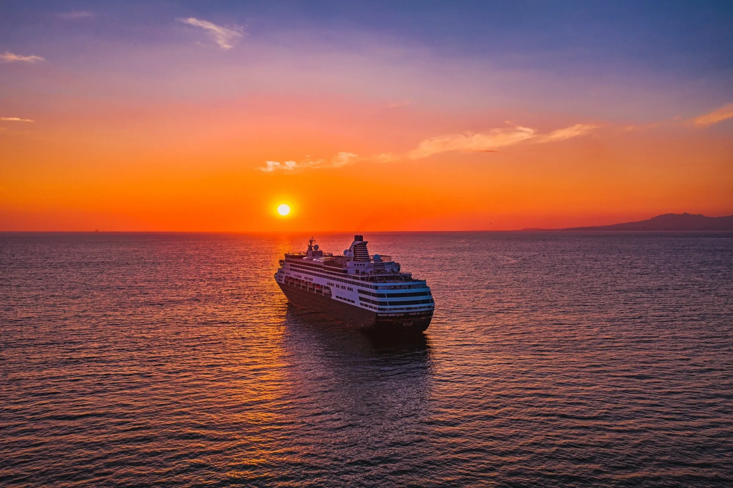 Sun setting over a cruise ship